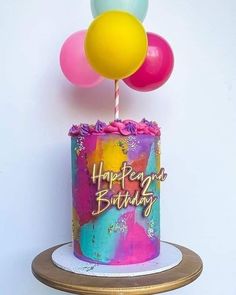 a colorful birthday cake with balloons on top