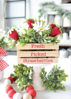 fresh picked strawberries in a wooden crate on top of a white table with greenery