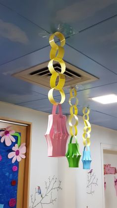 colorful paper lanterns hanging from the ceiling in an office space with flowers on the wall