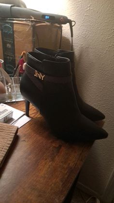 a pair of black boots sitting on top of a wooden table