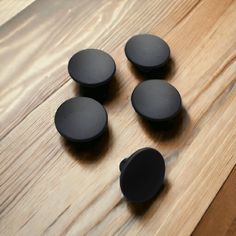 four black knobs are sitting on a wooden surface