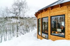 a woman sitting at a table in front of a window on top of snow covered ground