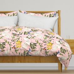 a bed with pink and green floral bedspread on top of wooden headboard