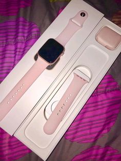 an apple watch is in its box on the bed with it's pink strap