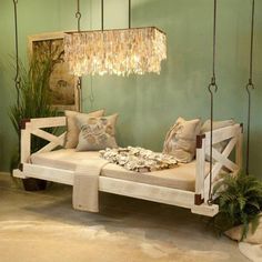 a swing bed with chandelier hanging from it's sides and pillows on the bottom