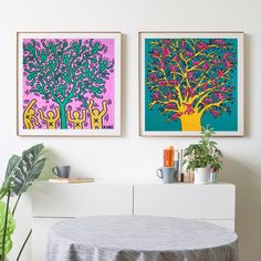 two paintings hang on the wall above a table with a plant in front of it