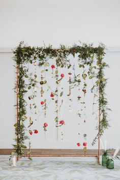 an arrangement of flowers and greenery hanging on a wall