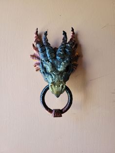 a dragon head hanging on the wall with a ring in it's mouth,