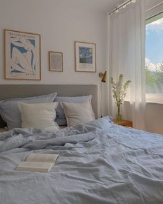 a bed with blue sheets and white pillows in a bedroom next to a painting on the wall