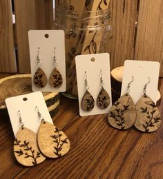 four wooden earrings are sitting on a table next to a jar with some wood slices in it