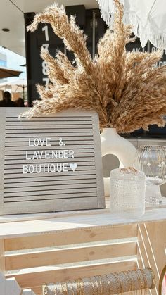 a sign that says love and lavender boutiquey on the side of a table with dried grass