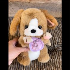 a person holding a small stuffed dog on top of a wicker table with an object in it's hand