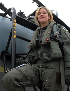 a female fighter pilot sitting in the cockpit of an airplane with her hand on her hip