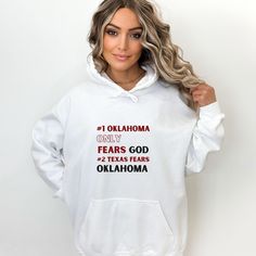 "Embrace the bold spirit of Oklahoma with this cozy and stylish hoodie, featuring the impactful quote by Danny Stutsman: \"#1 Oklahoma only fears God, #2 Texas fears Oklahoma.\" This statement hoodie not only showcases your Sooner pride but also offers a soft, smooth sanctuary as the temperatures dip. Available in neutral white and grey, this hoodie is crafted from a blend of 50% pre-shrunk cotton and 50% polyester, ensuring a comfortable wear with reduced pilling. The fabric weight of 8.0 oz/yd Game Day Cotton Hoodie Pre-shrunk, Game Day Sports Fan Fleece Hoodie, Oklahoma State Sweatshirt, Ou Sooners, Knit Cuff, Pocket Pouch, Stay Warm, Oklahoma, Rib Knit