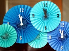 three blue and green paper fans with numbers on the sides are hanging in front of a window