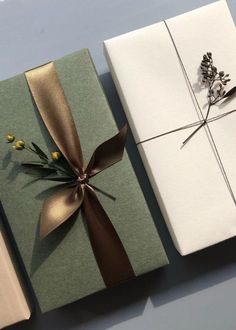 three wrapped gift boxes with ribbons and flowers on them