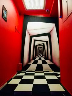 a long hallway with black and white checkered flooring, red walls and skylight