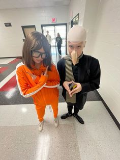 two mannequins dressed in orange and black standing next to each other on the floor