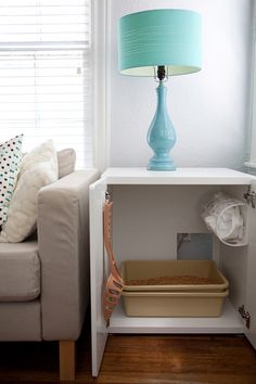 a blue lamp sitting on top of a white shelf next to a couch and window