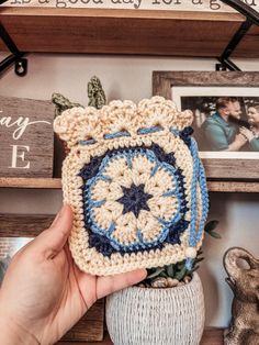 a crocheted pot holder sitting on top of a wooden shelf next to pictures