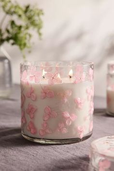 a white candle with pink flowers on it sitting on a table next to other candles