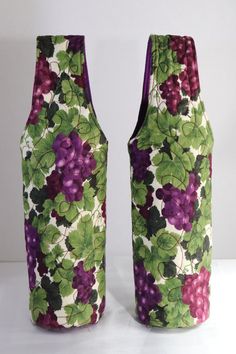 two vases with grapes and leaves on them, one is green and the other is purple