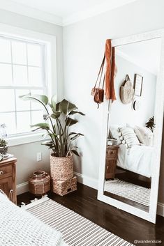 a bedroom with a bed, mirror and plants