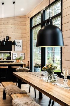 a dining room table and bench in front of a large window with wooden paneling