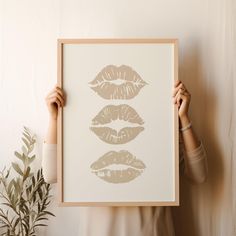 a woman holding up a framed art print with three lips