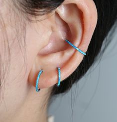 a close up of a person's ear with two small blue hoops on it