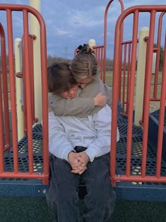 two people hugging each other while sitting on a playground equipment ride at the same time