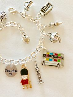 "Adorable London charm bracelet featuring 11 detailed silver charms of travel to London, England, classic landmarks, and British life. Hand stamped 1/2\" 18 gauge aluminum disc says \"London ❤️\". Memories of a visit abroad to bustling London Town! Charms include: suitcase, Lion royal crest, crown, Union Jack, Royal Guard, Big Ben, double decker bus, tea pot, umbrella, phone booth, and beer mug saying \"Cheers\". Charms are antique silver, silver tone, gold tone and enameled. Most are two-sided Silver Nickel-free Bracelet Souvenir, Nickel-free Silver Bracelets As Souvenir, Silver Charm Bracelet As Souvenir, So Long London Bracelet, London Necklace, London Pandora Charm, Paris Charm Bracelet, Paris Honeymoon, Paris Souvenirs