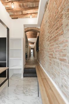 the hallway is lined with brick and white walls, along with built - in shelving