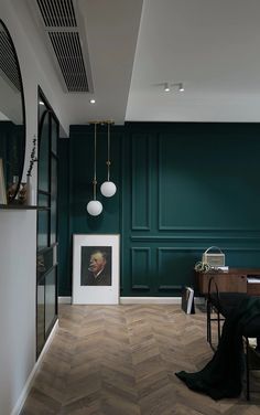 a room with green walls and wood flooring in the center, along with a painting on the wall