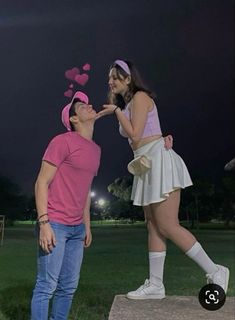 a man and woman standing next to each other in the grass with hearts drawn on their mouths