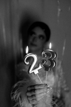 a woman holding two candles in front of her face with the number 28 on it