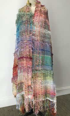 a multicolored shawl is displayed on a mannequin