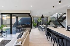 a living room filled with furniture next to a kitchen and dining room table covered in black chairs