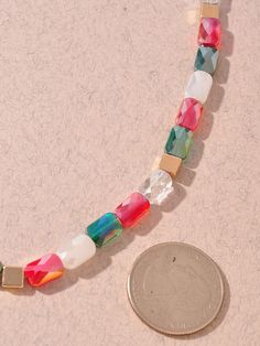 a coin sitting next to a necklace made out of glass beads and wood pieces on a table