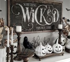 a mantle with candles, pumpkins and other halloween decorations on it in front of a sign that says wikid this way comes