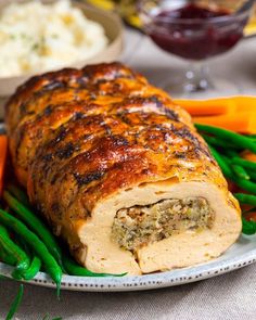 a meatloaf roll on a plate with green beans and carrots