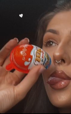 a close up of a person holding a candy bar in front of her face with a heart on it