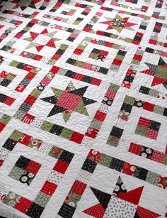 a quilted table topper with red, green and black stars