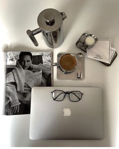 an open laptop computer sitting on top of a white desk next to a cup of coffee