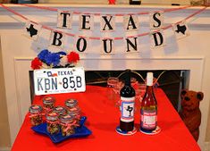 a red table topped with bottles of wine and desserts next to a fire place