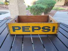 a wooden box with the word peps on it is sitting on a table outside