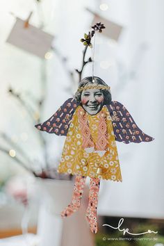 an ornament is hanging from a tree in front of a white vase filled with flowers