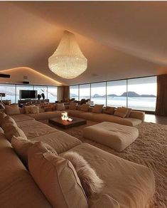 a living room filled with lots of couches next to a large window overlooking the ocean