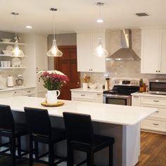 a kitchen with white cabinets and black chairs