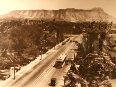 an old black and white photo of traffic on a snowy road in the mountainside